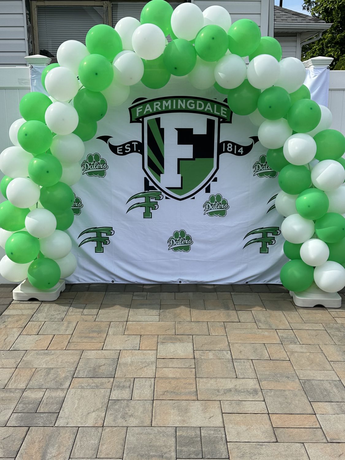 Green and white balloon arch around a custom printed backdrop