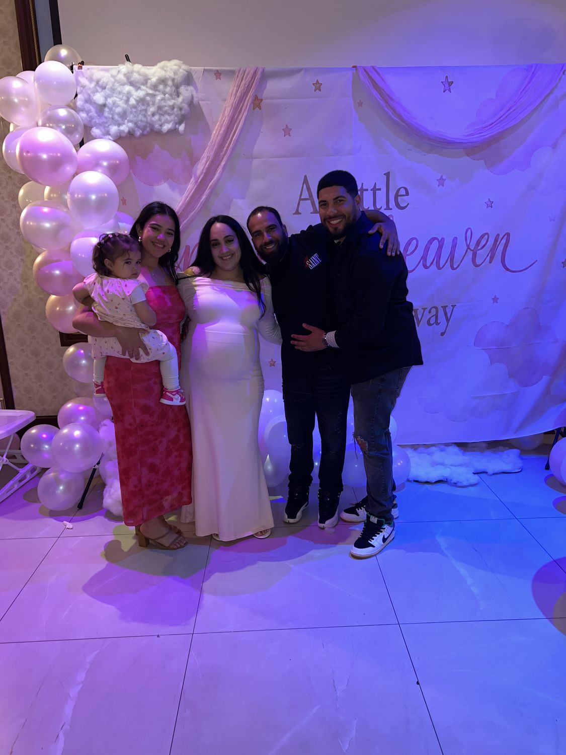Family at a baby shower in front of a pearl balloon backdrop