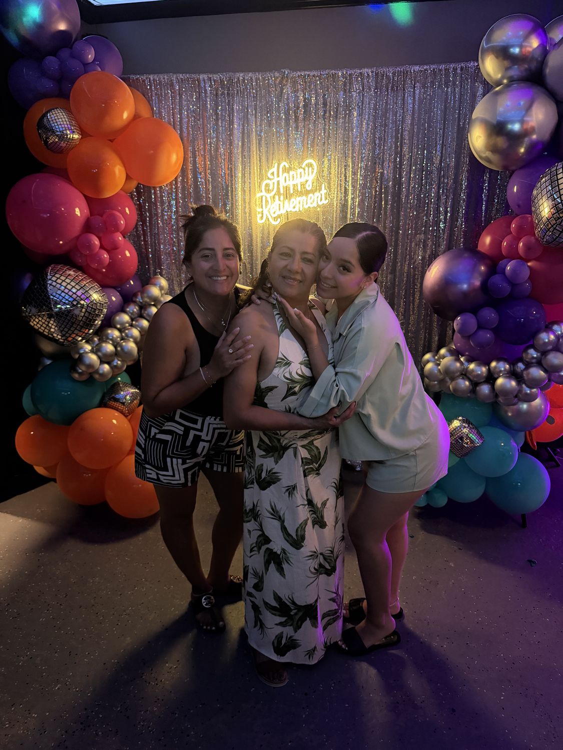 Guests posing in front of a colorful balloon garland and neon sign