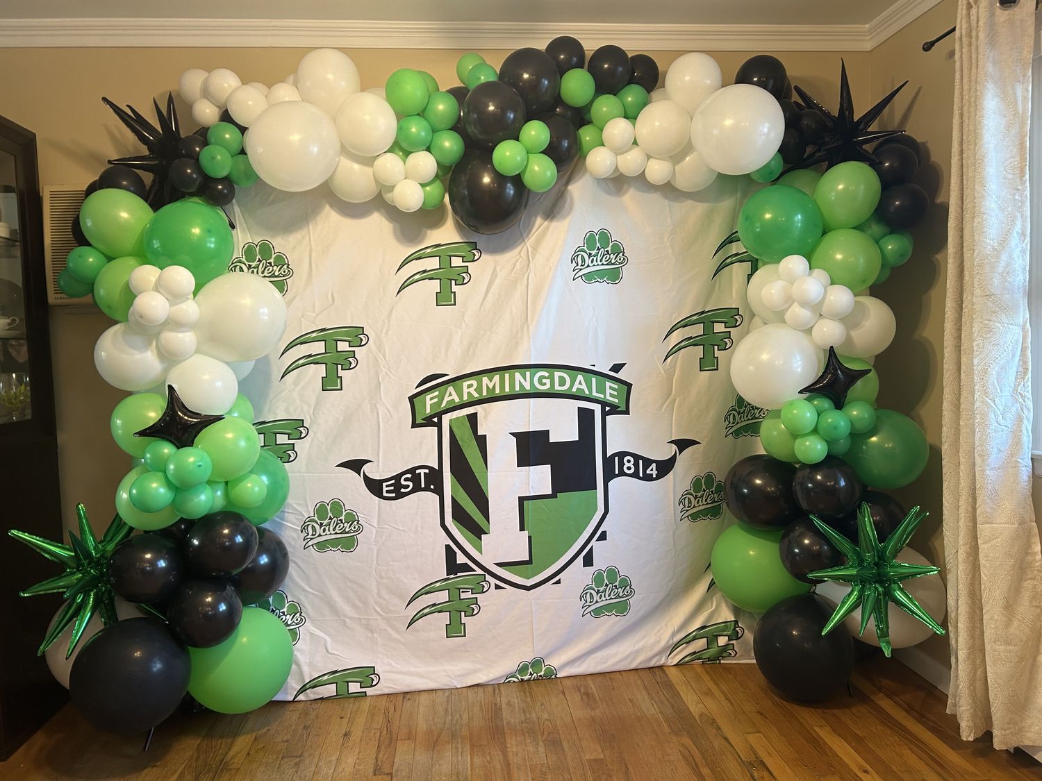 White, black and green balloon garland framing a custom printed school-spirit backdrop