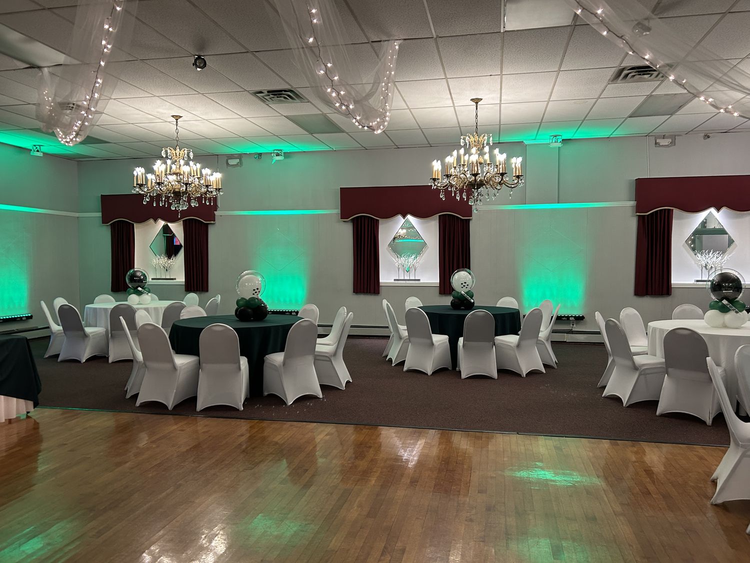 Banquet hall with white chair covers, round tables and teal uplighting