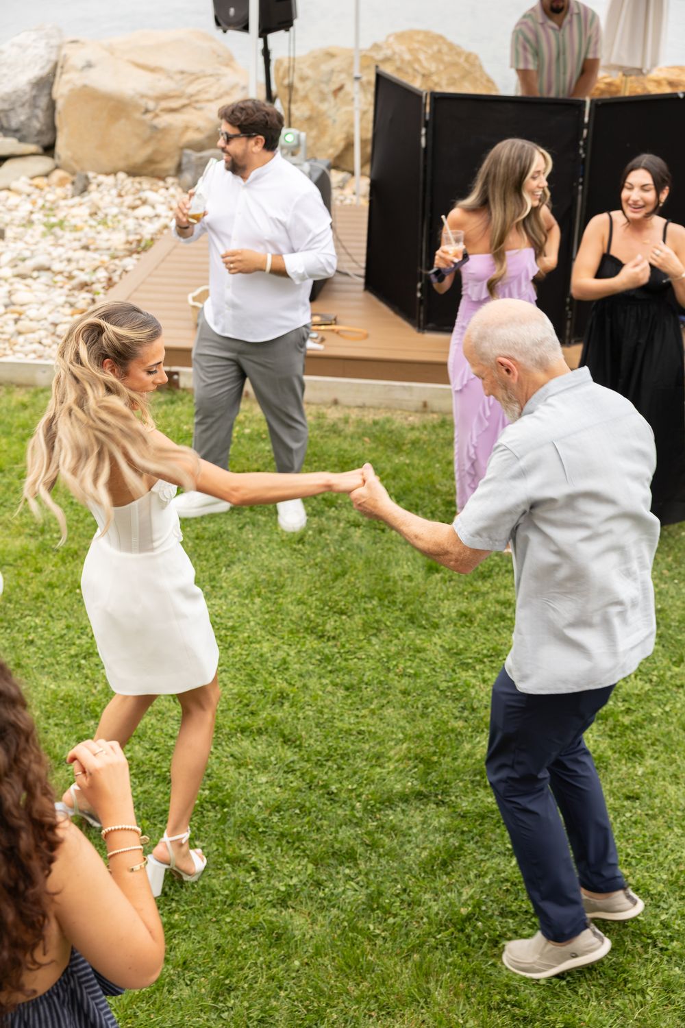 Guests dancing together on the lawn with the DJ booth behind them