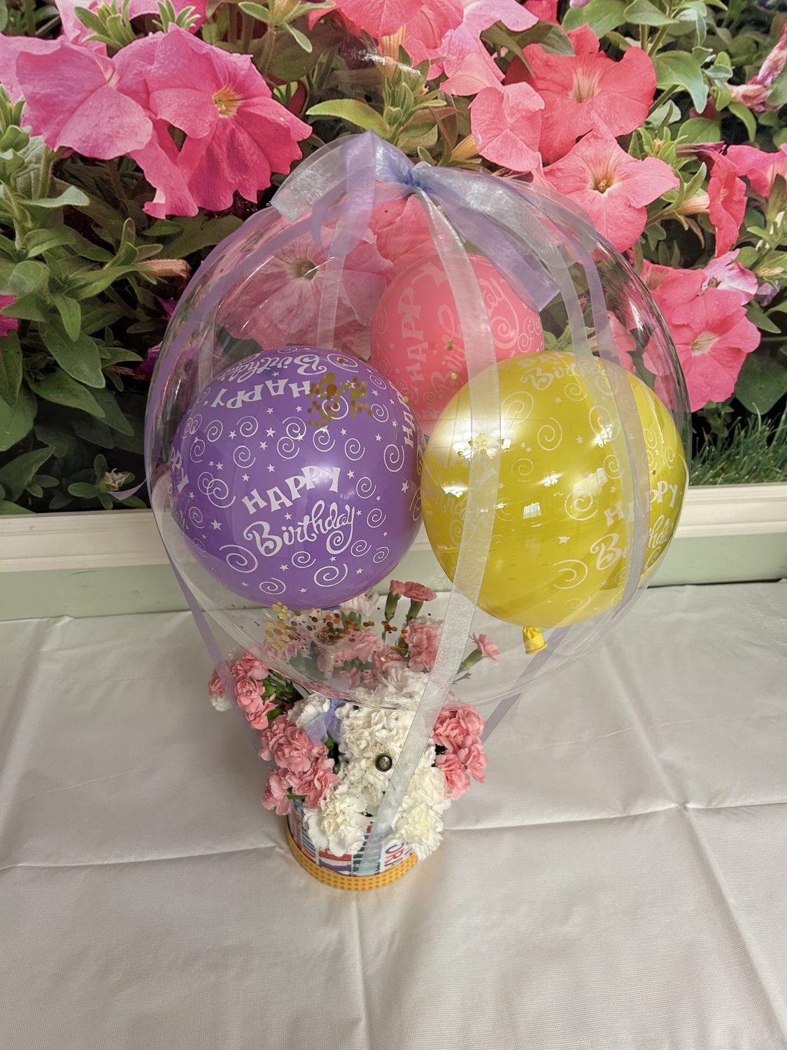 Clear bubble balloon bouquet with purple and yellow balloons on a white table