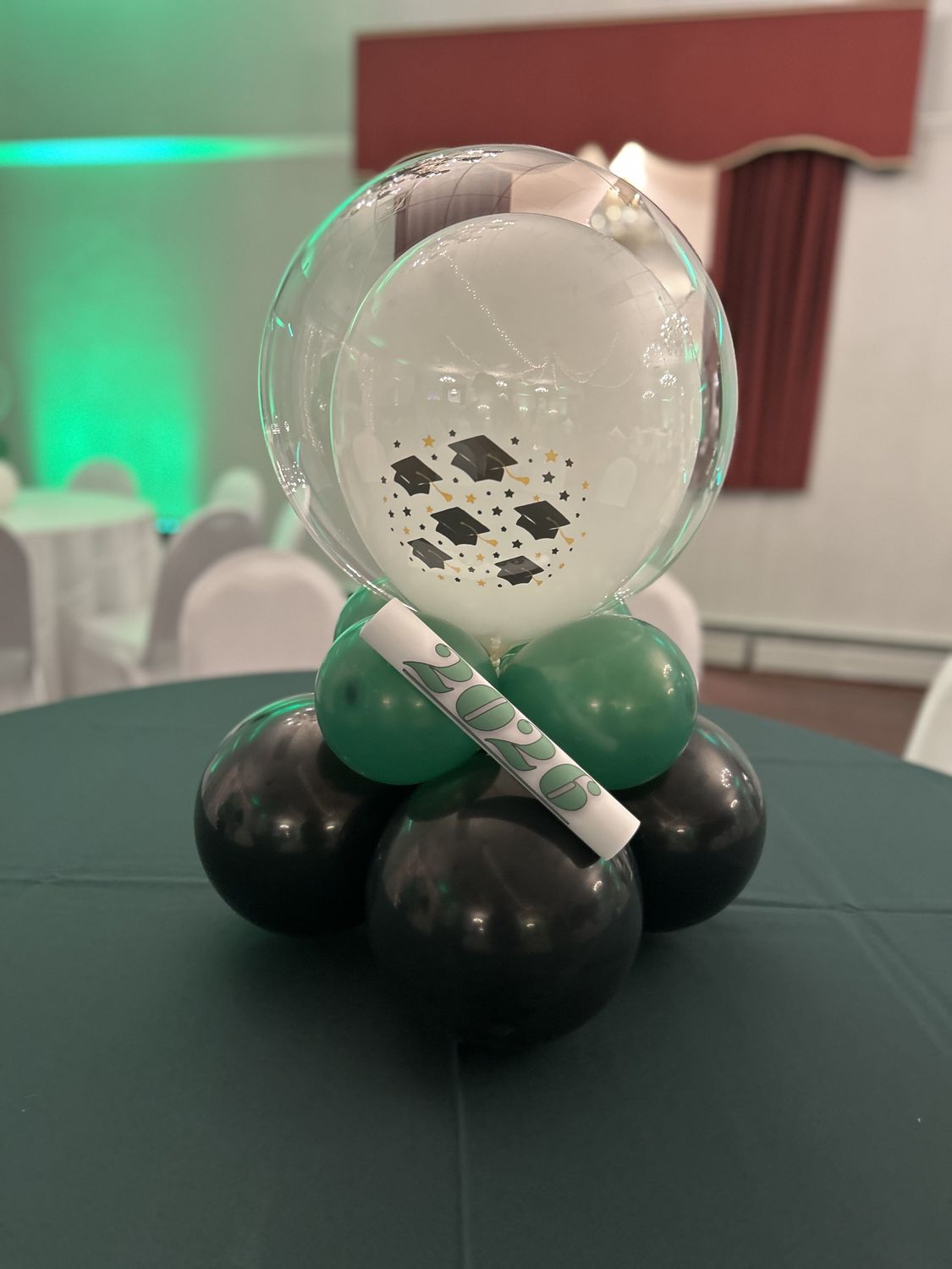 Graduation bubble balloon centerpiece on a dark green tablecloth