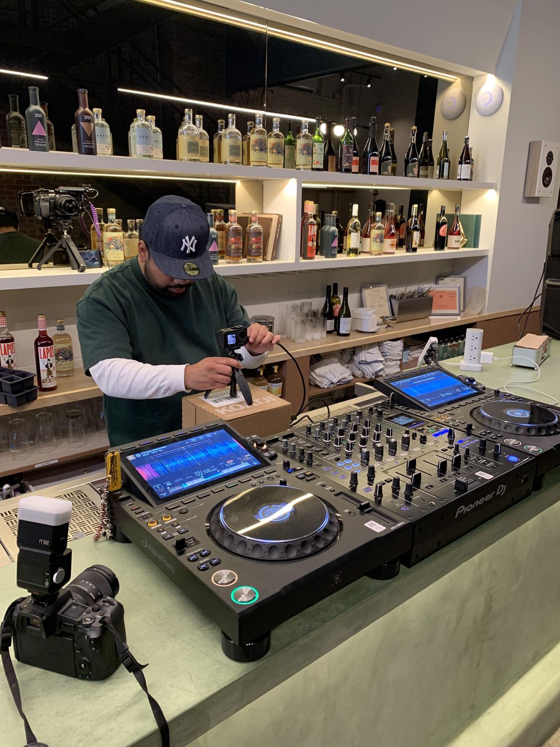 DJ at a bar with shelves of bottles behind him