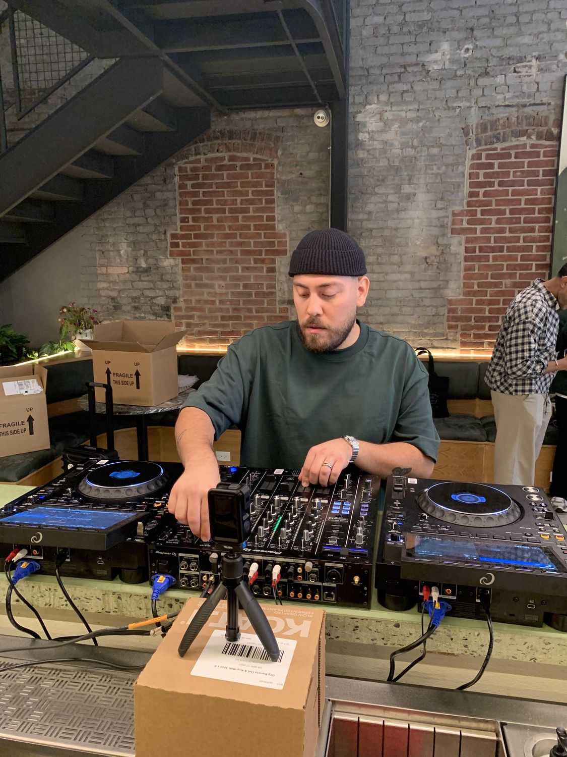 DJ performing at a café venue with exposed brick walls