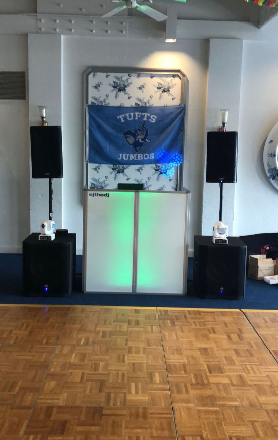 DJ booth with green uplighting and speakers on a parquet floor