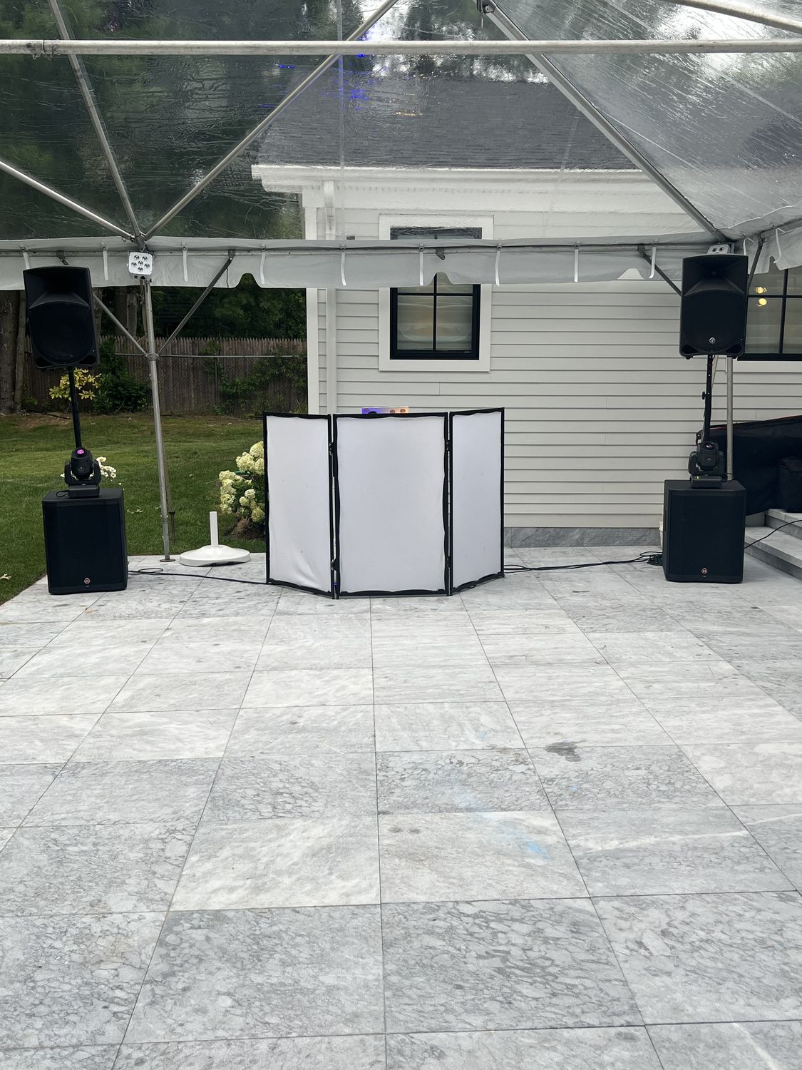 White DJ facade with speakers under a clear tent