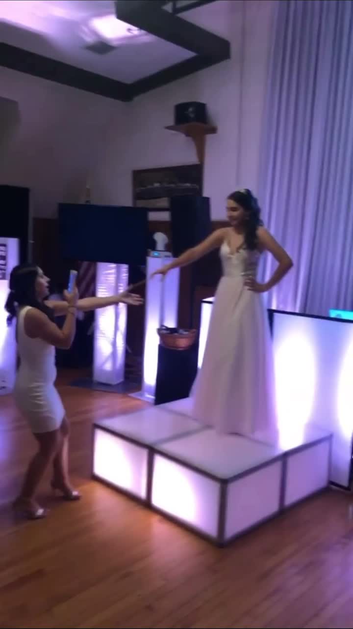 Bride dancing on a lit riser at a reception