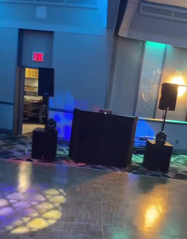 DJ booth with speakers over a blue-lit dance floor