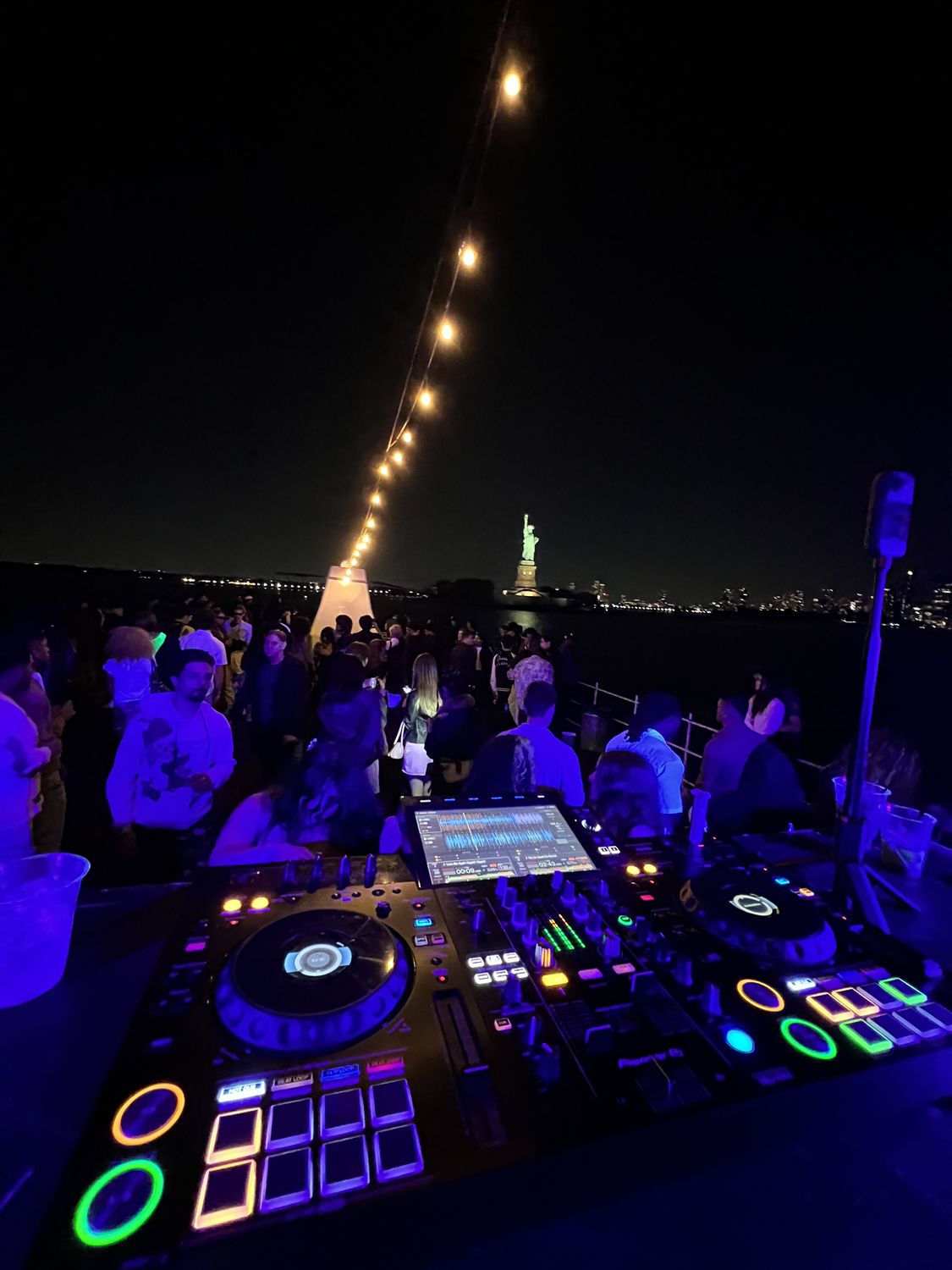 DJ controller lit up at a night event with the skyline behind