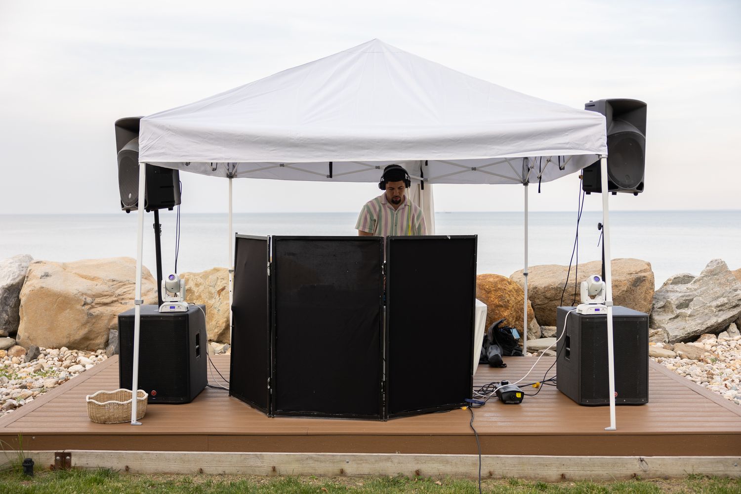 DJ booth under a white canopy tent beside the shoreline