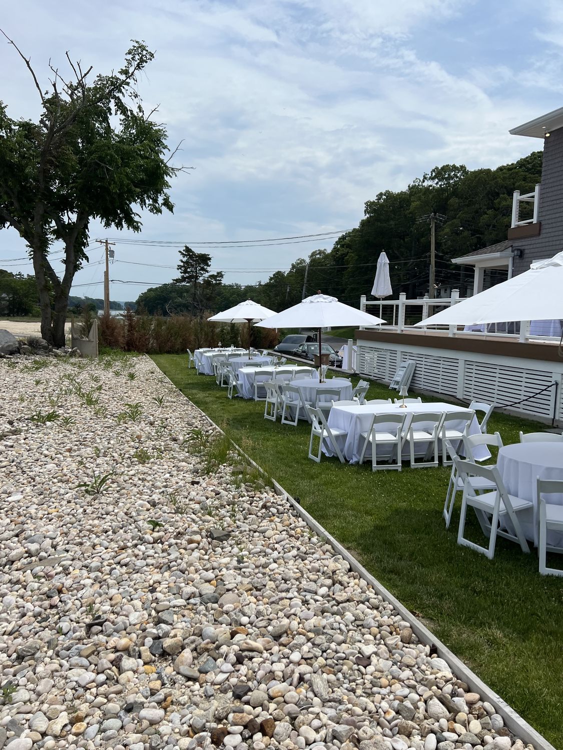 White tents with tables and chairs set up beside the water